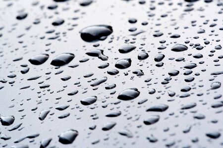 summer rain, drops of water on the car paint. a small round or pear-shaped portion of liquid that...
