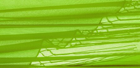 Background texture of silk fabric. This is a natural green salad scarf, this beautiful nylon satin made of artificial silk with a transparent hand and a wonderful sheen is perfect for your projects.の写真素材