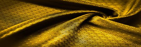 Background texture, pattern. Yellow, mustard silk fabric with a small checkered pattern. Muffled...
