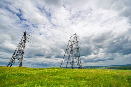 Summer landscape, high-voltage poles by the river, gloomy sky in the clouds, electricity erosionの写真素材