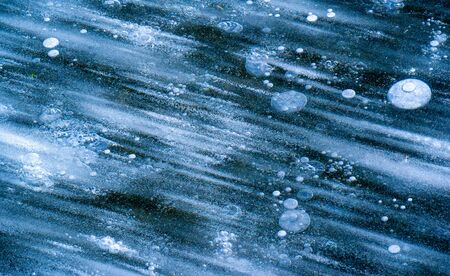 There is frost on the street, ice on the river, ice bubbles stuck in ice, unusually colorful ice architectureの写真素材