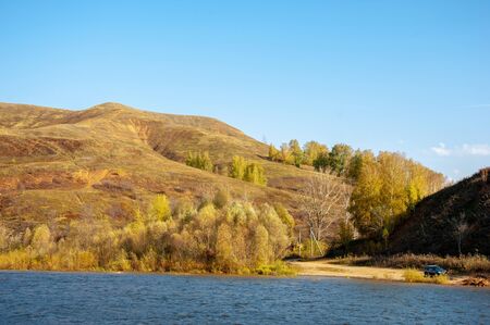 Autumn landscape, dark blue water, last warm days, river, trees, windy weather, yellow-red autumn...