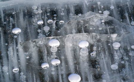 There is frost on the street, ice on the river, ice bubbles stuck in ice, unusually colorful ice architectureの写真素材