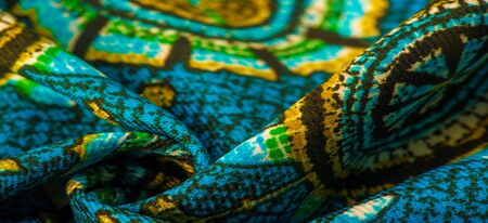Texture background design, turquoise silk fabric with yellow drawings of flowers circles. Charmeuse...
