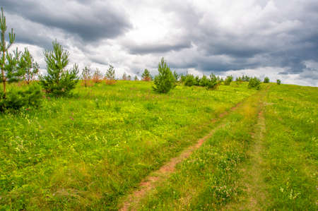 summer photography, green grass, powerful thunderclouds, blue sky, tourist walk along the Kama Riverの写真素材