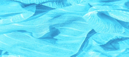 Silk fabric. Texture of blue wrinkled fabric. Blue wrinkled, wavy surface texture. Close-up, soft...