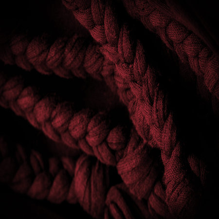 Texture, background, pattern. Fabric in red braids. Knitted knitted background with embossed...
