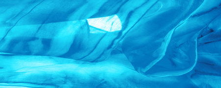 Blue fabric streaked with gray spots on a turquoise background. Abstract designer fabric fancy...