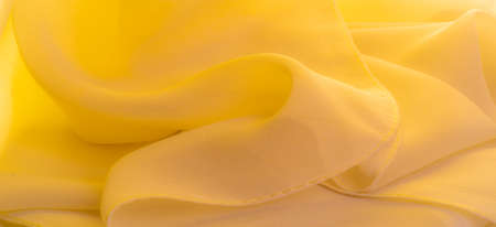 Texture. template. yellow silk polyester. Background from yellow silk fabric. Textured background made of transparent and light fabric for sewing clothes. Panorama from textiles.の写真素材