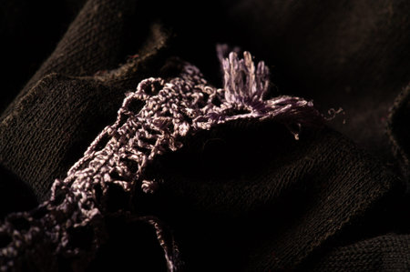 Dark brown woolen scarf. with a sewn-on lace on a strip. Texture. Background. Template