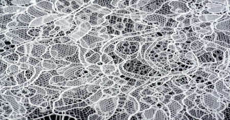White lace fabric on a black background. Our collection of lace fabrics, delightfully embroidered pieces, vintage pieces are sure to excite and awaken the lace-loving fashionistas inside you.の写真素材