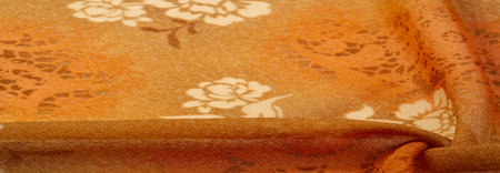 Texture, background, design. Orange silk fabric with floral print. Clothing design. Modern floral...