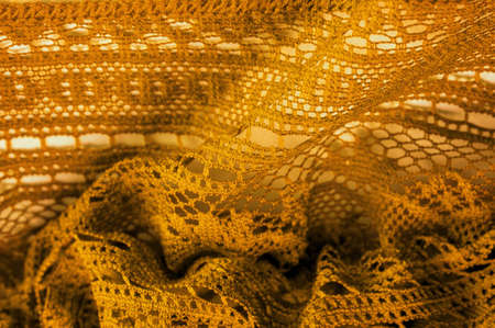 Yellow lace fabric, a thin open fabric, usually of cotton or silk, made using loops, twisting or knitting threads into patterns. Background texture, pattern.の写真素材