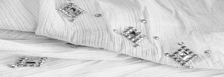 Silk pattern, white fabric with glued decorative faceted stones. texture background with bright...