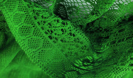Green lace fabric, thin open fabric, usually cotton or silk. Green wrinkled lace on white spandex background, macro view. Background texture, pattern.の写真素材