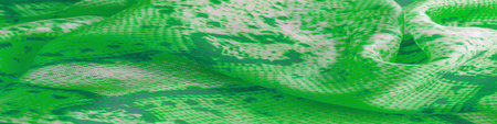 green fabric with snakeskin pattern, background texture of bright green fabric close up. background,...