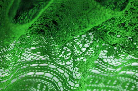 Green lace fabric, thin open fabric, usually cotton or silk. Green wrinkled lace on white spandex background, macro view. Background texture, pattern.の写真素材