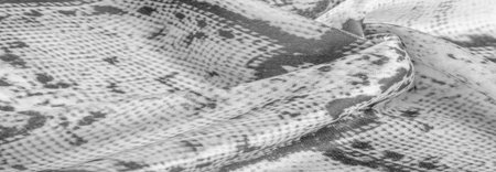 gray monochrome fabric with snakeskin pattern, background texture of bright gray fabric close up....