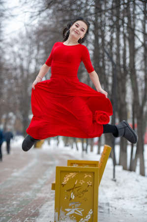 winter photography, a girl in a red long dress, black boots, photographed outdoors in the parkの写真素材