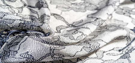 Silk fabric in black and white with lace pattern. This elastic lace trim adds softness to everything! Texture, background, pattern.の写真素材