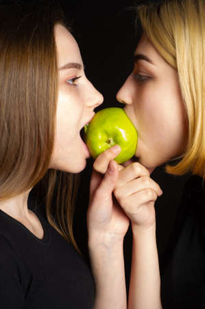 Blondes in black T-shirts on a black background. Eat a green apple. A bone of contention is the core, or the core of the dispute, or a small issue that can lead to a larger dispute.の写真素材