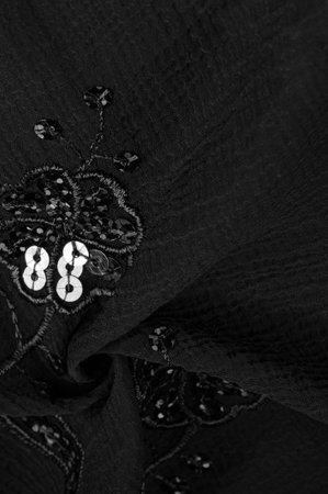 Silk black. The fabric is embellished with sequins. background, silk satin, luxurious texture, dark...