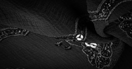 Silk black. The fabric is embellished with sequins. background, silk satin, luxurious texture, dark fabric, costume cotton material, abstract color image pattern, delicate liquid charcoal velvetの写真素材