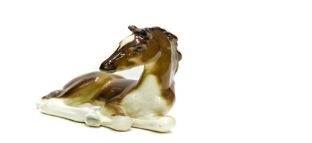 Antiques, art, collectibles. Swap meet. Isolated over white background. figurine of a horse lying on the floor, glazed ceramicsの写真素材