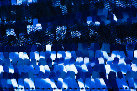Sequins in blue. Ribbon for fabric decoration. Background texture, sunrise. Smooth slope of rows of round sapphire sequins on a fine mesh of fabric.の写真素材