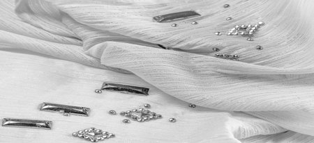 white fabric with glued decorative faceted stones. texture background with bright colorful stones,...