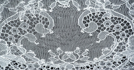 White lace fabric on a black background. Our collection of lace fabrics, delightfully embroidered...