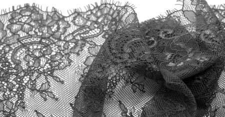 Black lace fabric on a white background. Fancy African polyester and tulle lace fabric with flowers for your design. Texture. Background. Templateの写真素材