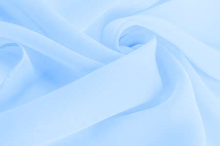 Light blue silk polyester. Background from aqua color silk fabric. Textured background made of transparent and light fabric for sewing clothes. Textile panoramaの写真素材