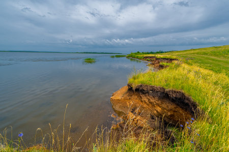 The floodplain of a large river is covered with green vegetation. Dirt road of local importance. Beautiful blue sky. Summer landscape photography. European part of the land. fields, meadows, ravines.の写真素材
