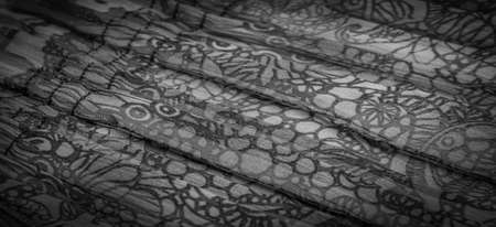 Black silk fabric, floral pattern. Wavy corrugation. Fine wave on the surface of the fabric. Background texture, decorative ornamentの写真素材
