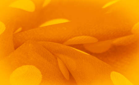 Yellow silk fabric with polka dots, circular dots on the fabric in the shape or approximately resembling a circle. Background texture, decorative ornamentの写真素材