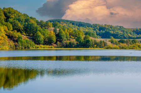 Autumn landscape, deciduous forest. With the onset of autumn, when the trees change color. It seems as if the artist painted the trees in different colors, capturing an idealistic landscape.の写真素材
