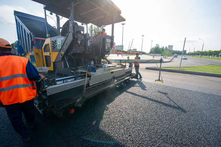 Road construction. At a construction site, workers spread the hot mixture onto the roadway and compact it. 12 07 2021 Kzakhstan Central Asiaのeditorial素材