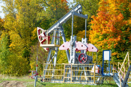 Oil rig pump rocking chair against the background of the autumn forest and sunset. Fuel, natural...