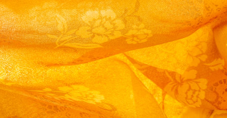 Orange silk fabric with floral print. Clothing design. Modern floral background. Modern exotic jungle plants. Tinted, sunlight effect Texture, background, design.の写真素材