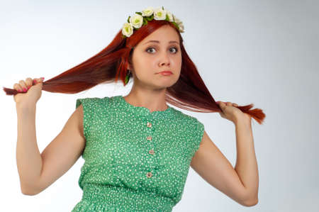 Young woman in sadness, disappointment, surprise. Children's spontaneity. Redhead red hair. Green dress tied with a beltの写真素材