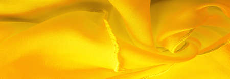 Yellow silk organza with wavy piping. Border around the edge of the fabric. Abstract background. texture pattern. Silk organza has a delicate open weave. Wave background. Copy spaceの写真素材