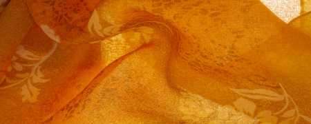 Orange silk fabric with floral print. Clothing design. Modern floral background. Modern exotic...