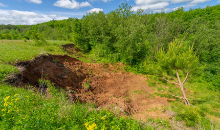 Dangerous landslide in a field on a sunny spring day.