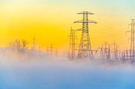 Beautiful and atmospheric scene of a winter morning. High voltage power lines add an element of...