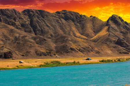 Feel the tranquility of a serene sunset over the river. Enjoy breathtaking views of majestic mountains and lush green trees. Immerse yourself in the beauty of nature in all its glory.の写真素材