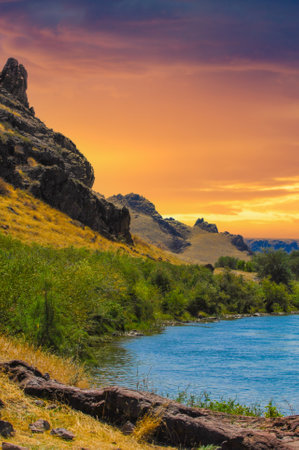 the peaceful calm of the sunset over the serene river. Immerse yourself in the beauty of majestic mountains and lush green trees. An ideal place to relax, meditate or simply enjoy the beauty of natureの写真素材