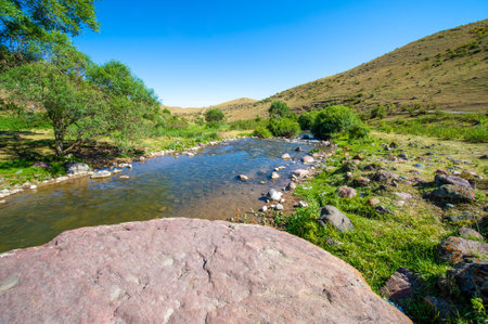 Enjoy the serene beauty of nature. Listen to the soothing sounds of a flowing river. Feel the calming effect of being surrounded by majestic mountains.の写真素材