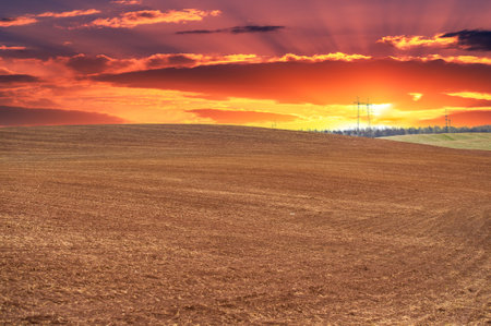 Experience a moment frozen in time, where a plowed field meets the vast expanse of a spectacular sunset. Admire the sheer beauty of this rural landscape.の写真素材