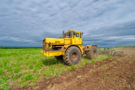 Spring photography, landscape with agricultural machinery, a tractor plows the land, plows a field, birds fly over arable landの写真素材